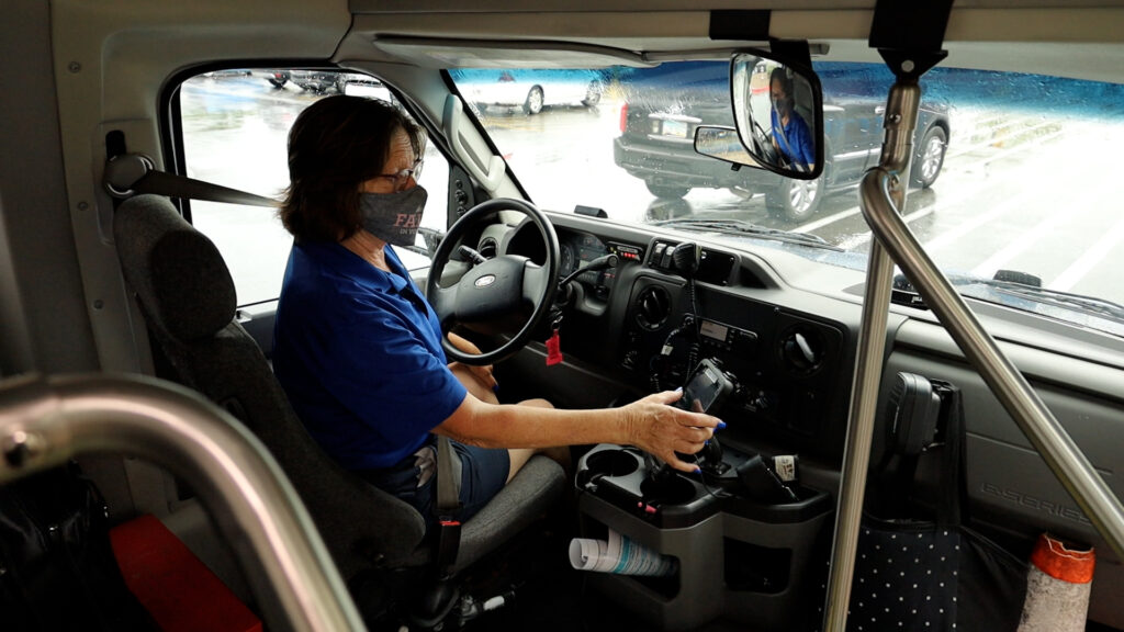 Sun On Demand driver Michelle checks destination information on a dash tablet inside the transit vehicle.