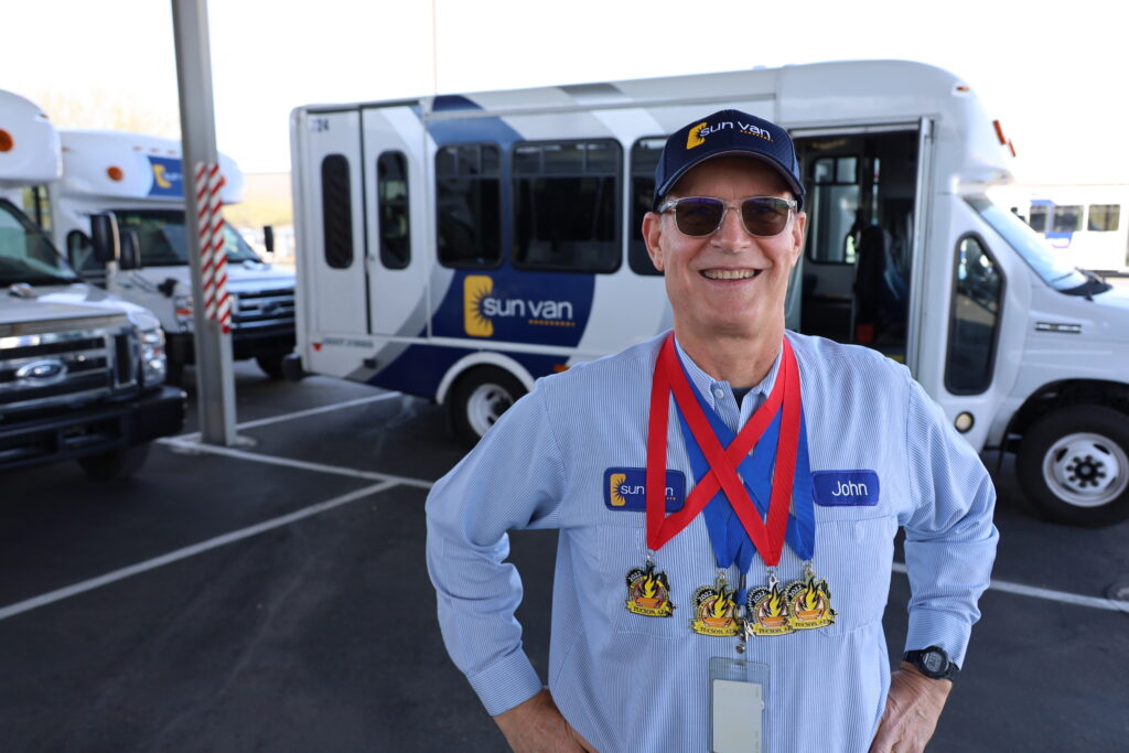 Sun Van driver John Spicker shows off his swimming medals.