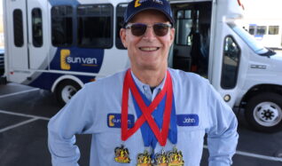 Sun Van driver John Spicker shows off his swimming medals.