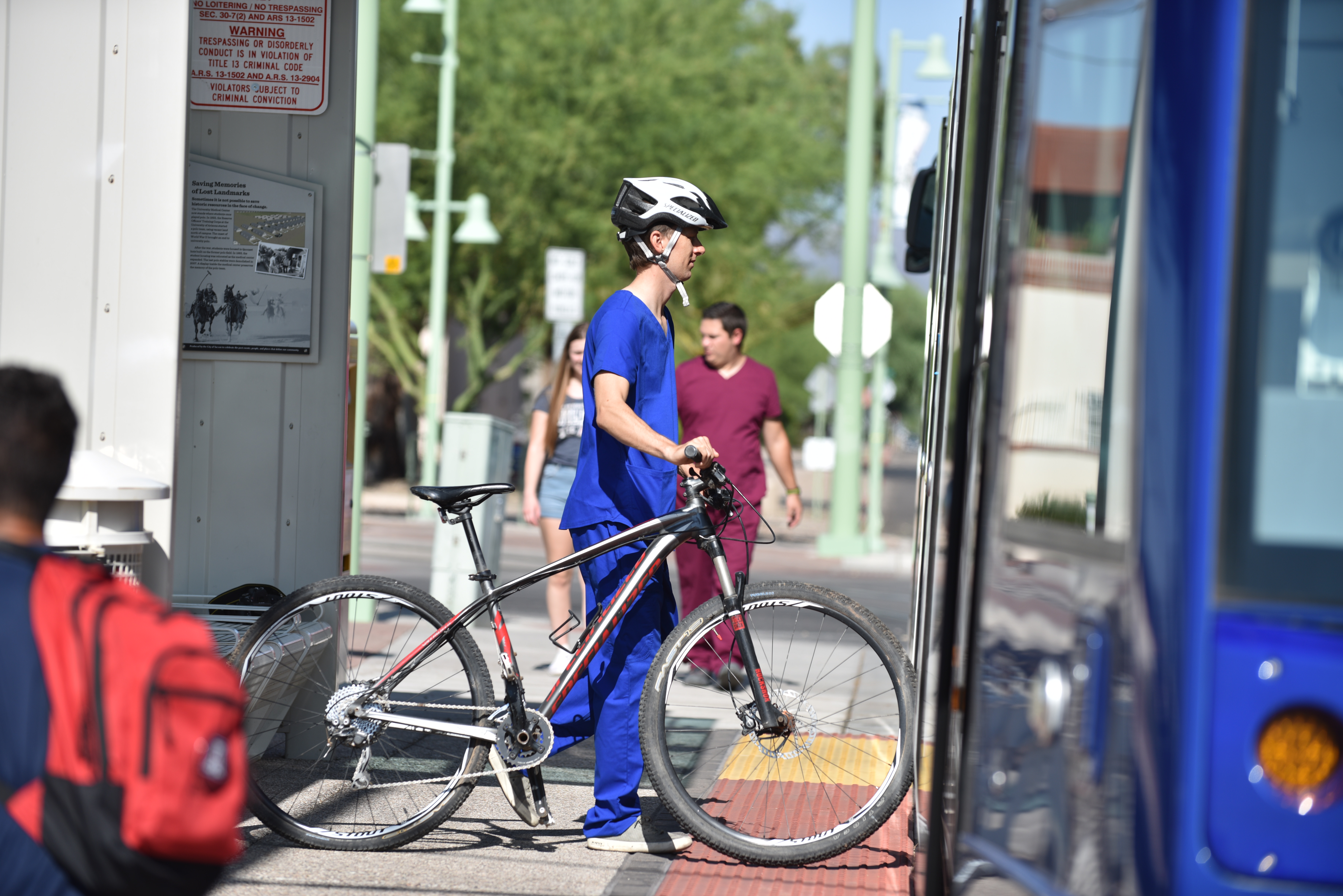 bright sunny day, passengers headed to Sun Link Streetcar and passenger getting on streetcar with bike.